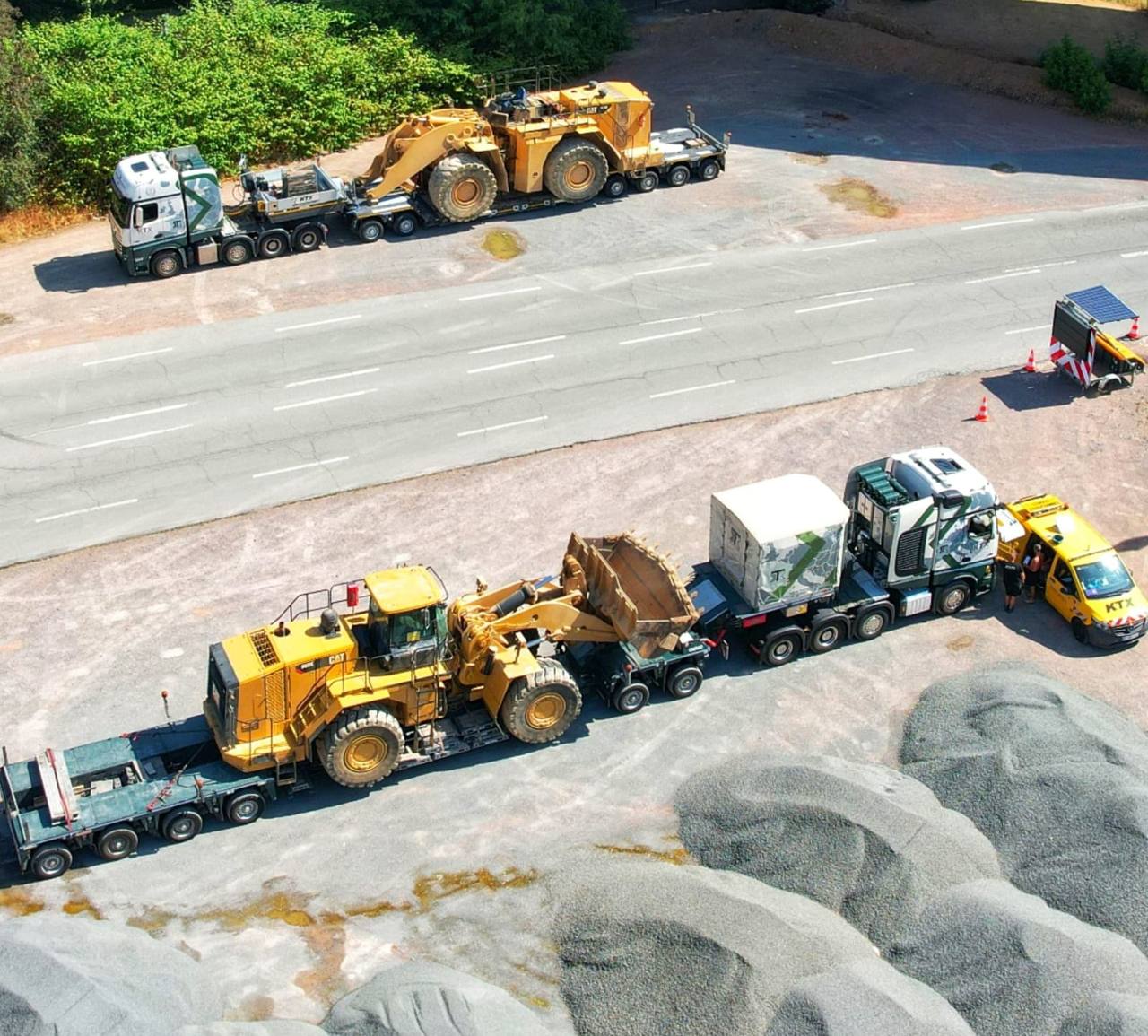 Deux ensembles porte-engins KTX Transport chargés de chargeuses sur pneus Caterpillar, escortés par un véhicule pilote KTX
